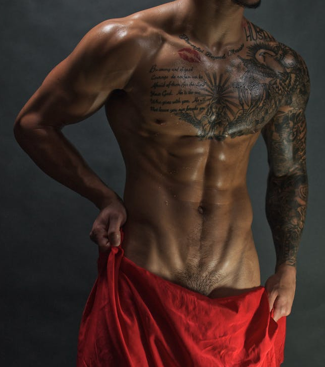 a tattooed naked man wearing a santa hat